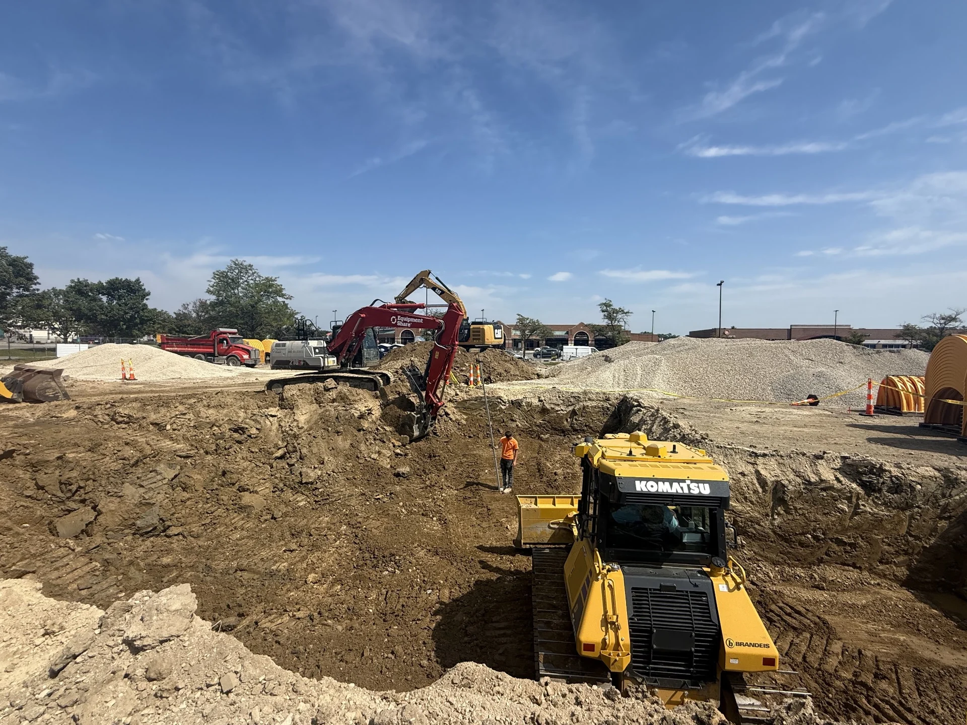 Dozer and excavator shaping a large excavation on a commercial construction site