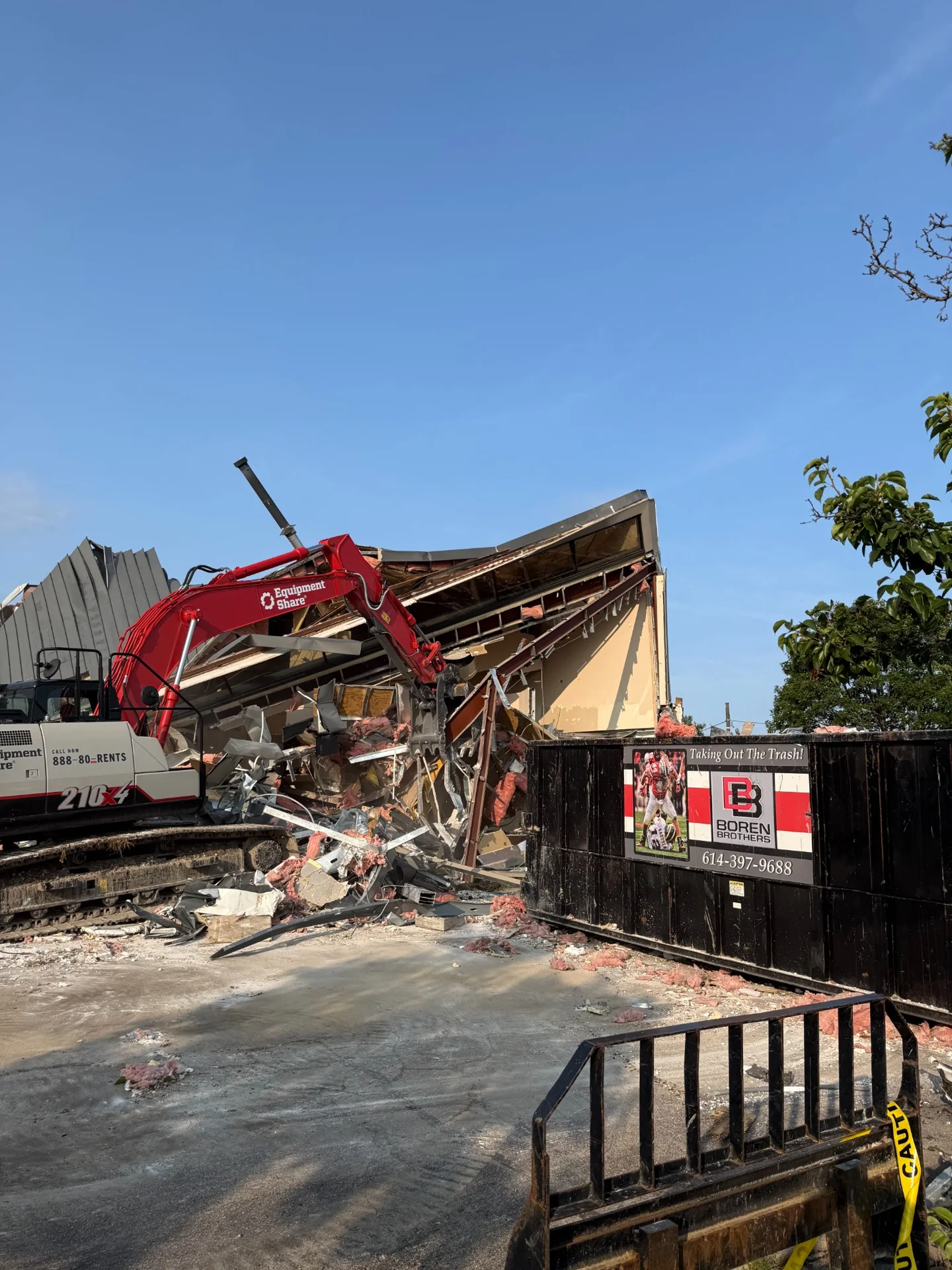 Red excavator working beside a structure during demolition