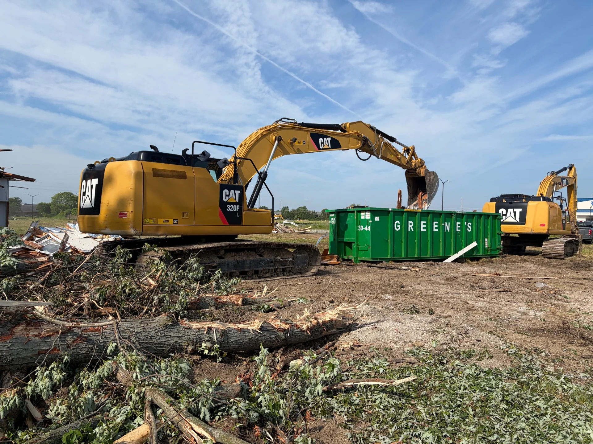 CAT excavators working beside a debris container during site clearing