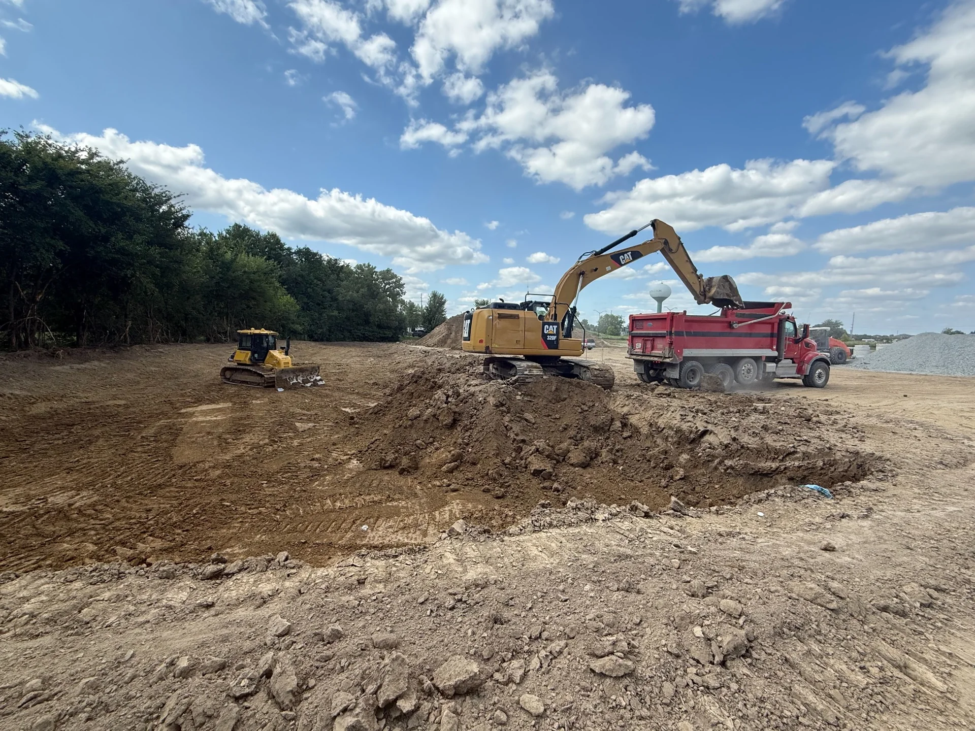 Dozer and excavator performing earthwork across a commercial site