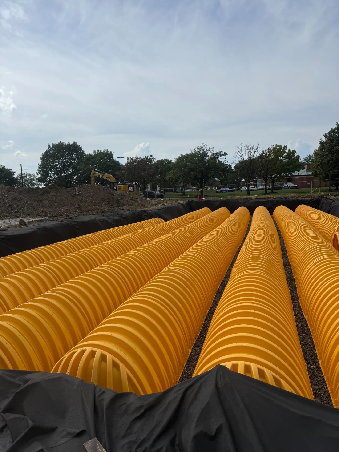 Yellow stormwater storage chambers arranged in rows inside an excavation